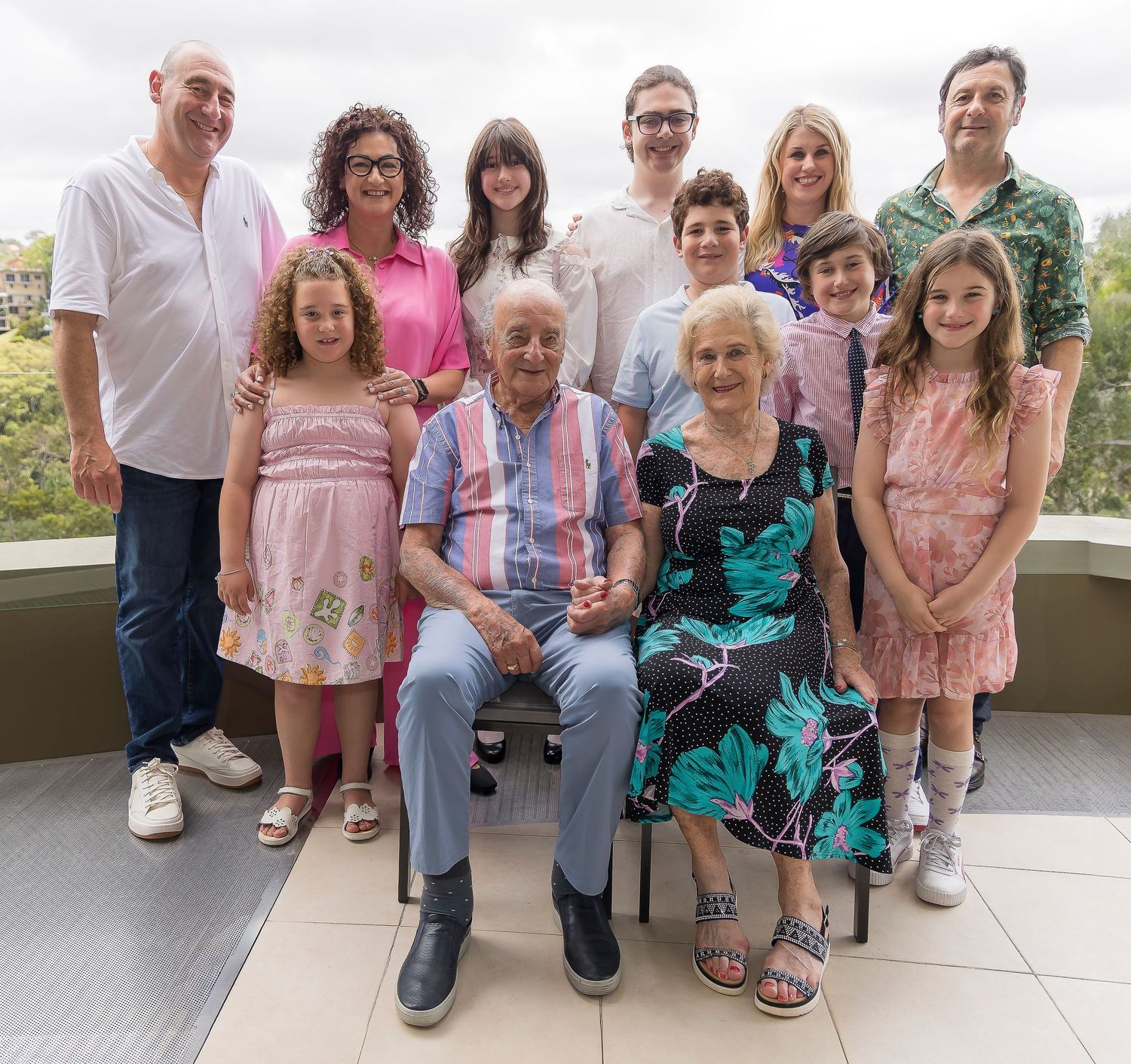 Multi-generational family gathering poses together on outdoor patio.