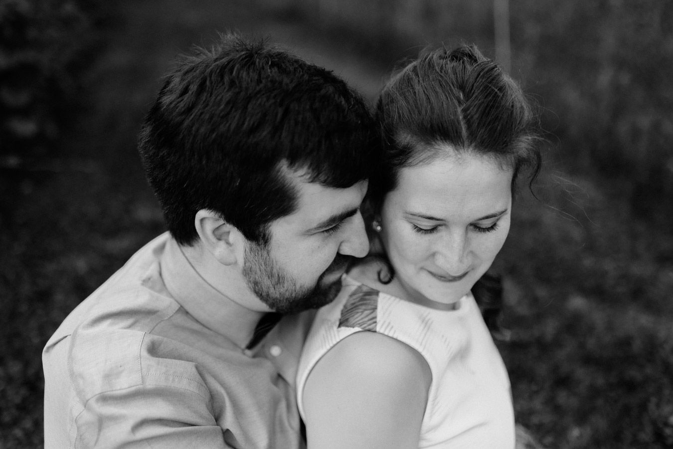 Intimate black and white portrait of a couple sharing a tender moment outdoors.