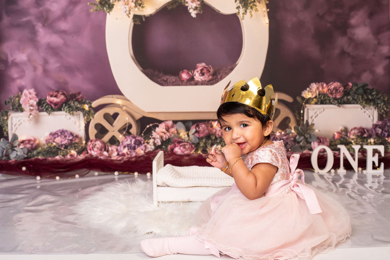 Pink princess themed first birthday photo setup with floral decorations and vintage aesthetic.