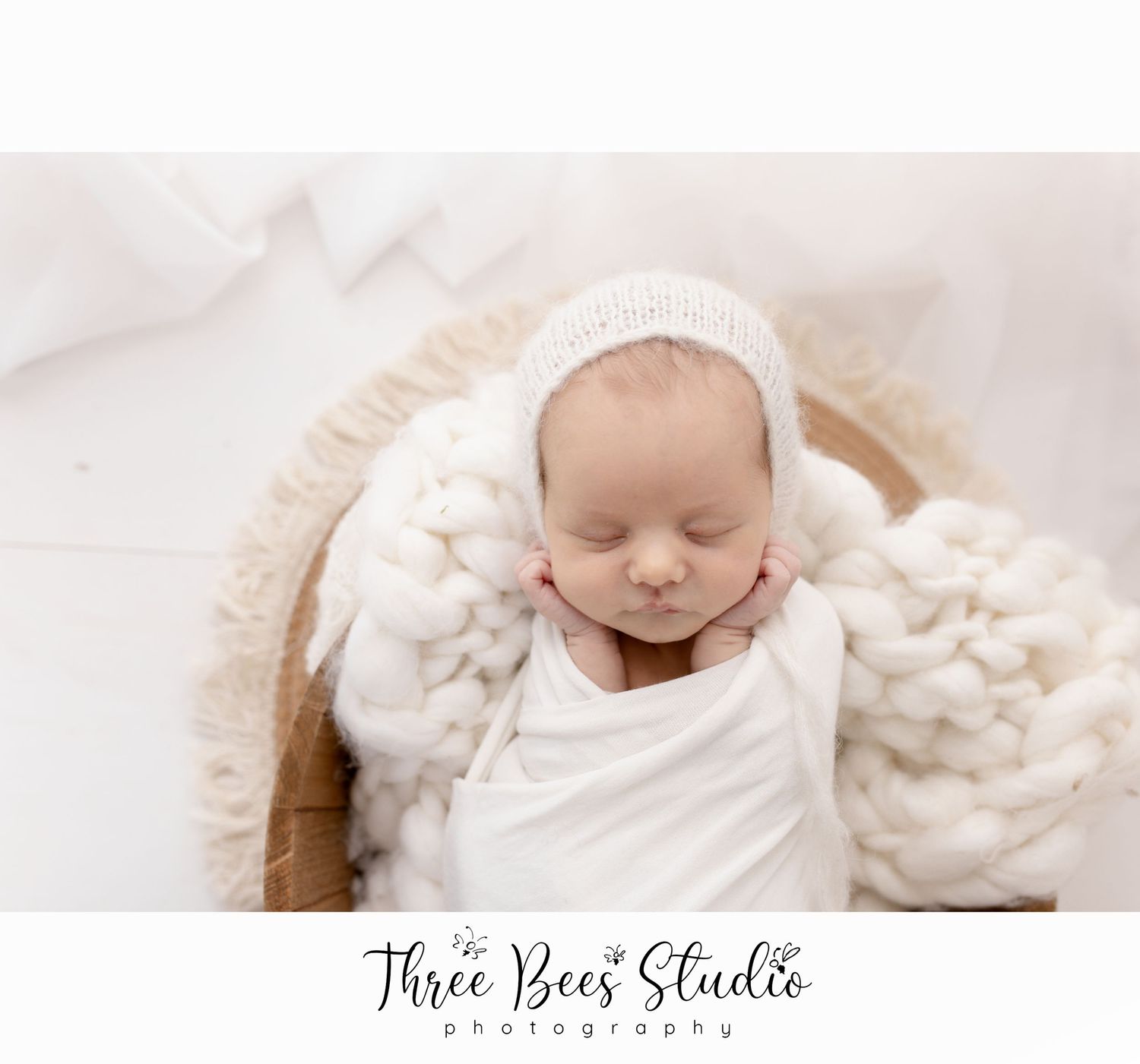 Peaceful sleeping newborn in white wrap on knit textile backdrop.