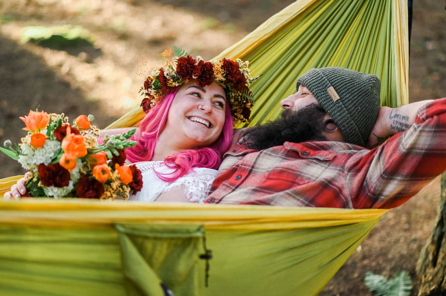 Bride and groom with flowers relaxing in hammock.