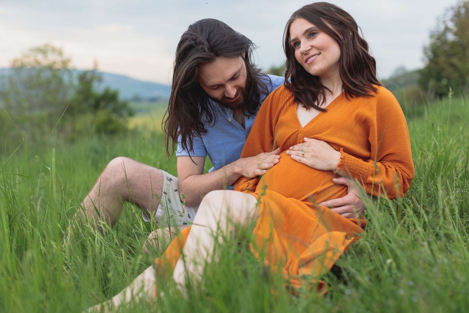 Christina and Doug sat in a field with her bump on show and Doug rubbing her pregnant belly