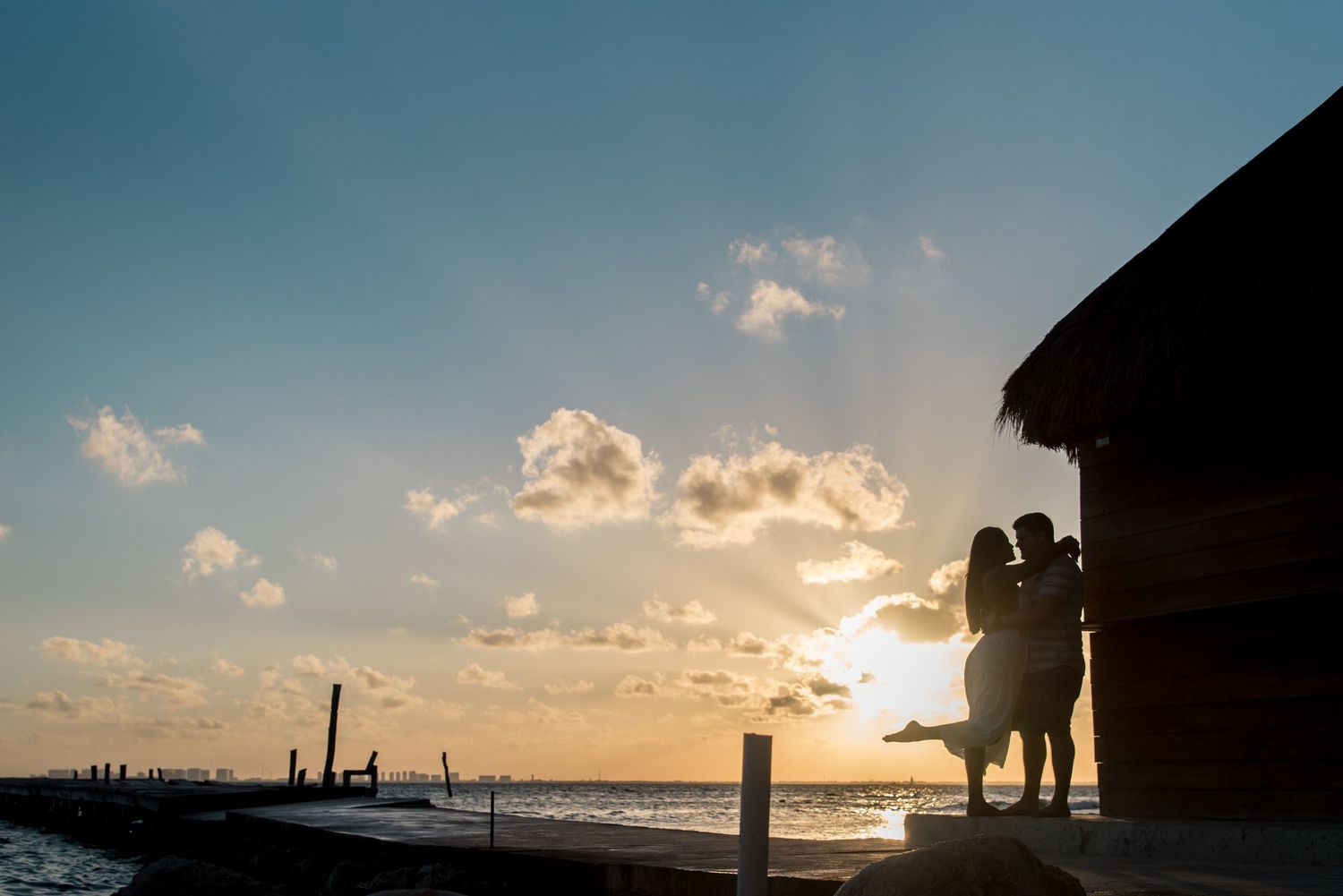 Romantic shot of the couple standing against the Isla Mujeres, Mexico sunset