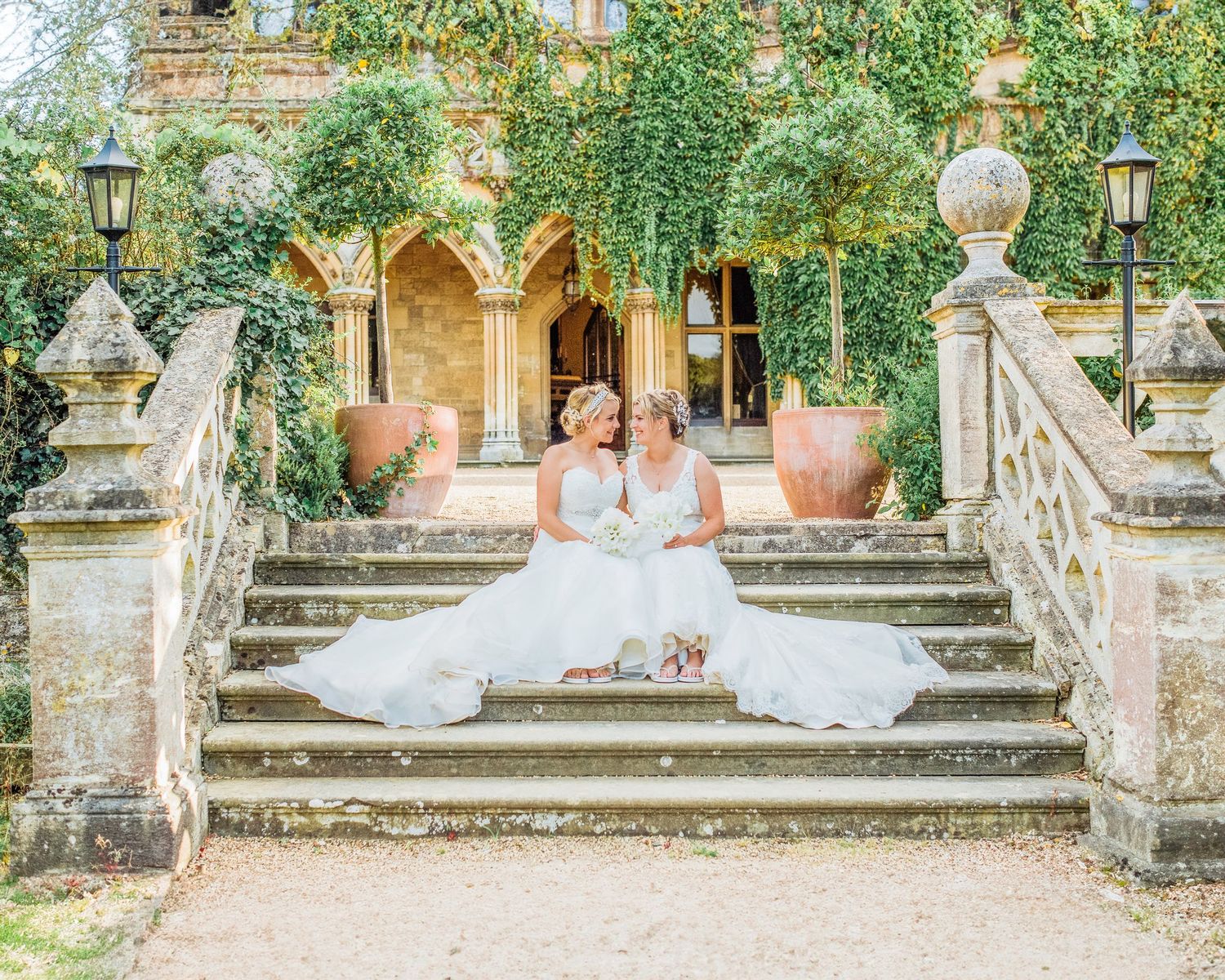 Hayley Elizabeth Photography manor by the lake, two brides sat on steps luxury wedding cheltenham gloucestershire