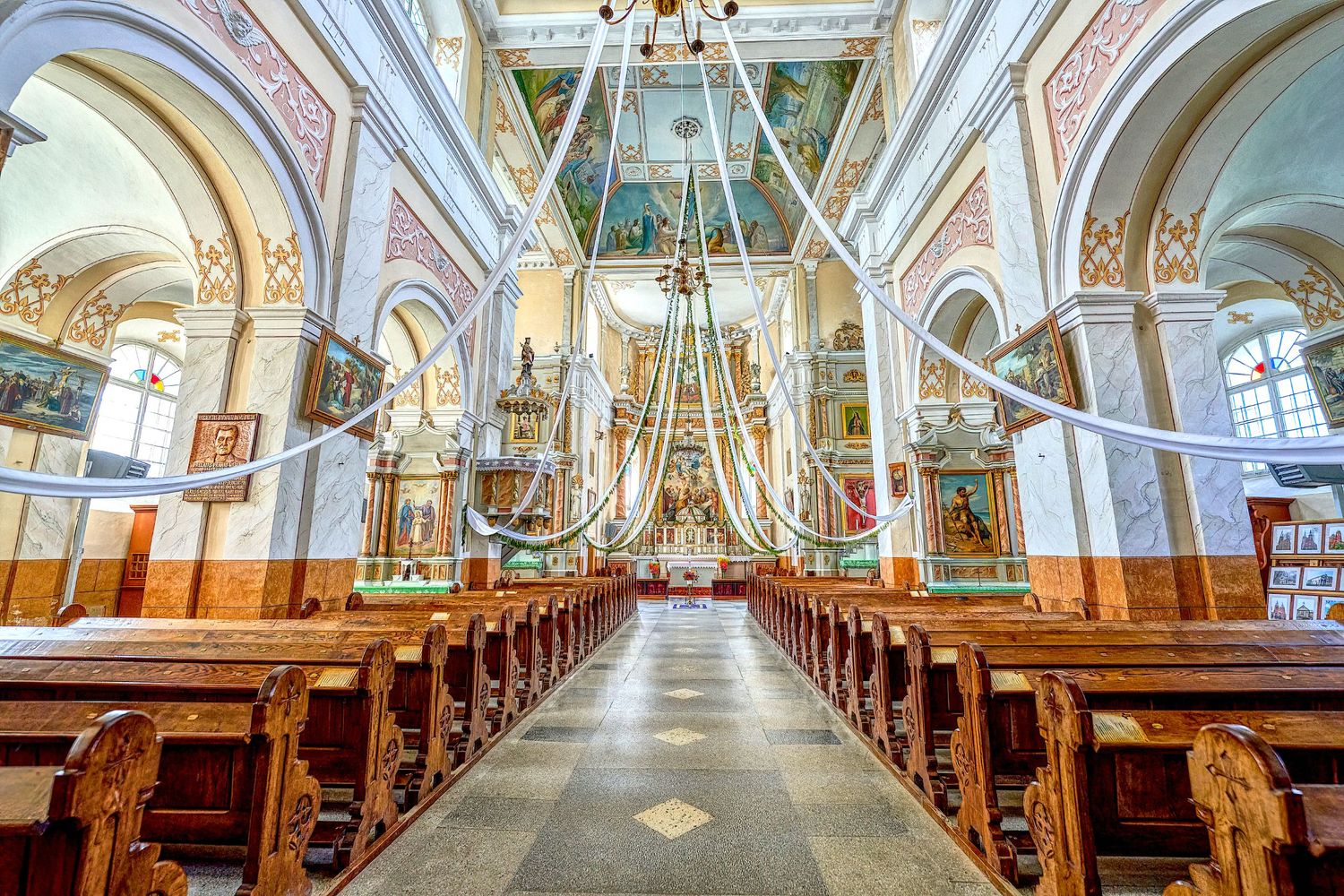 Elegant church interior featuring vaulted ceilings, ornate architecture and traditional wooden pews.