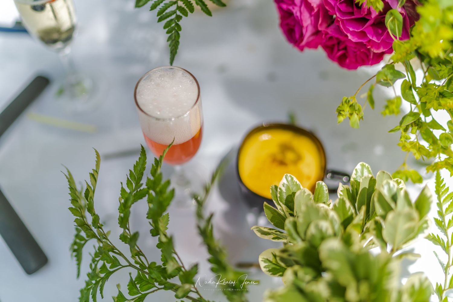 Close-up view of colorful floral arrangements with pink roses and greenery next to cocktails.