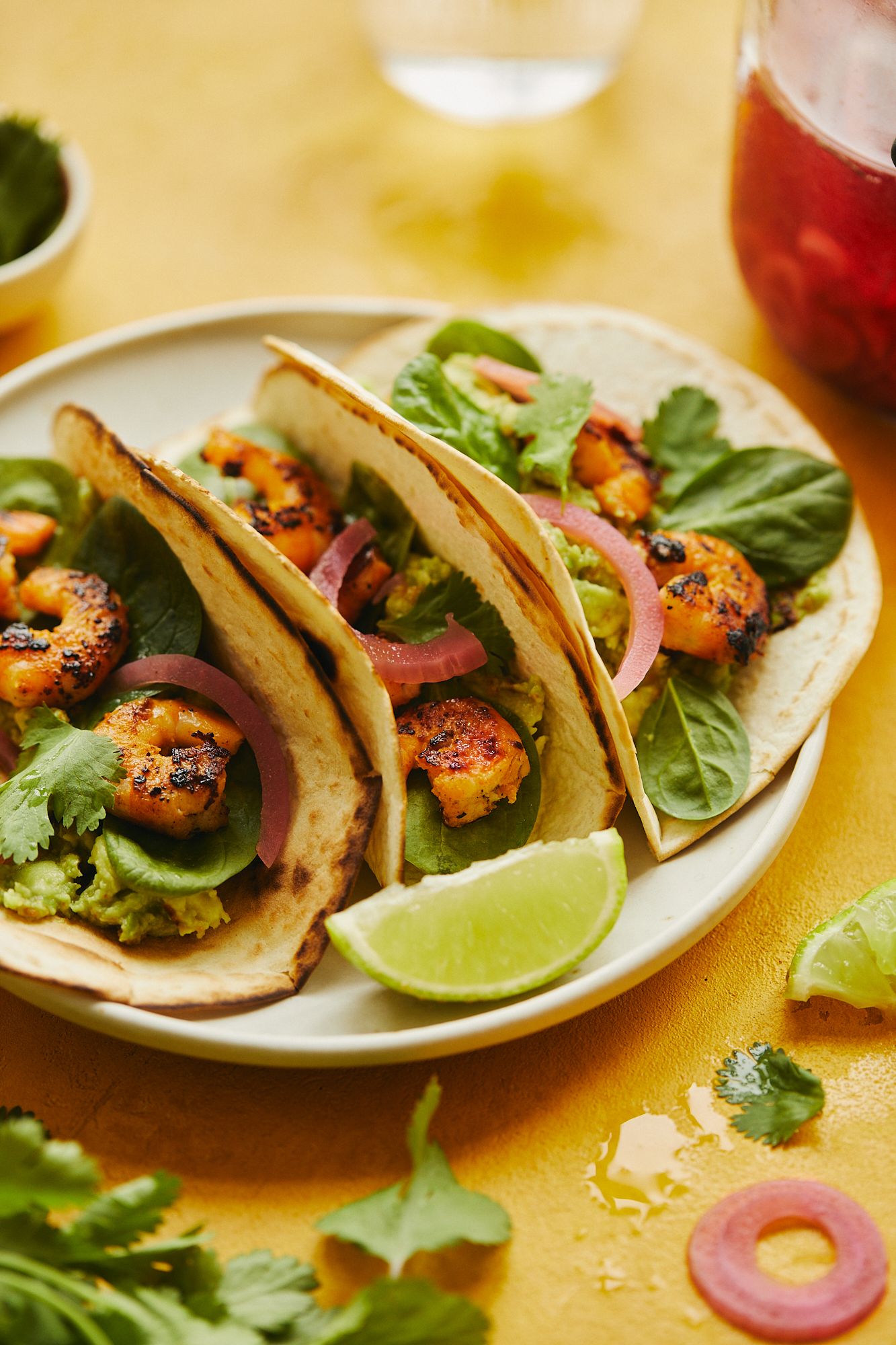 Grilled shrimp tacos with fresh greens, pickled onions and lime wedges.