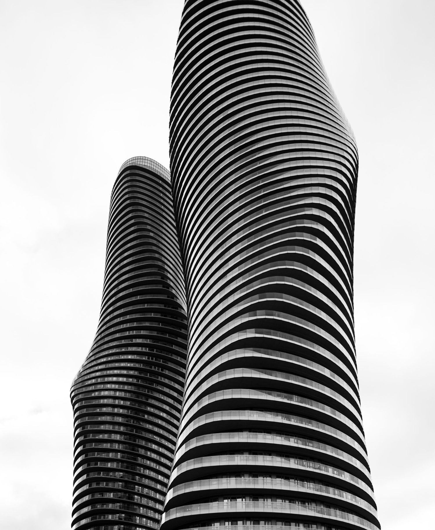 Modern curved skyscrapers with distinctive ribbed architecture shot in dramatic black and white.