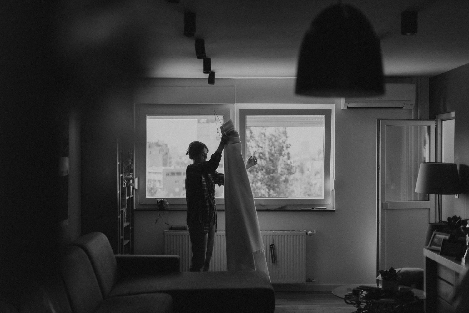 Black and white silhouette of people at a window in an interior setting.