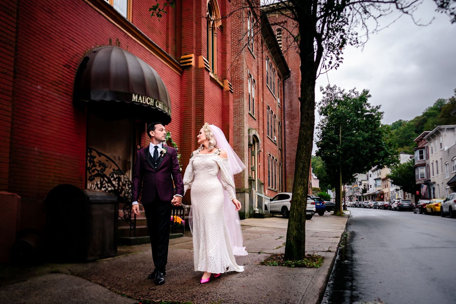 Red brick building exterior creates dramatic backdrop for wedding photography.