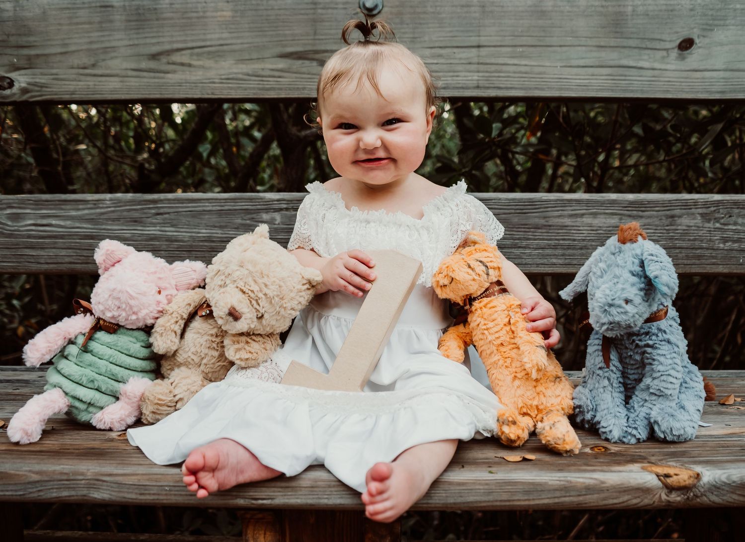 Outdoor Cake Smash Session at Indian Rocks Beach, Indian Rocks, FL; Baby holding a 1 sign surrounded by Winnie the Pooh stuffies
