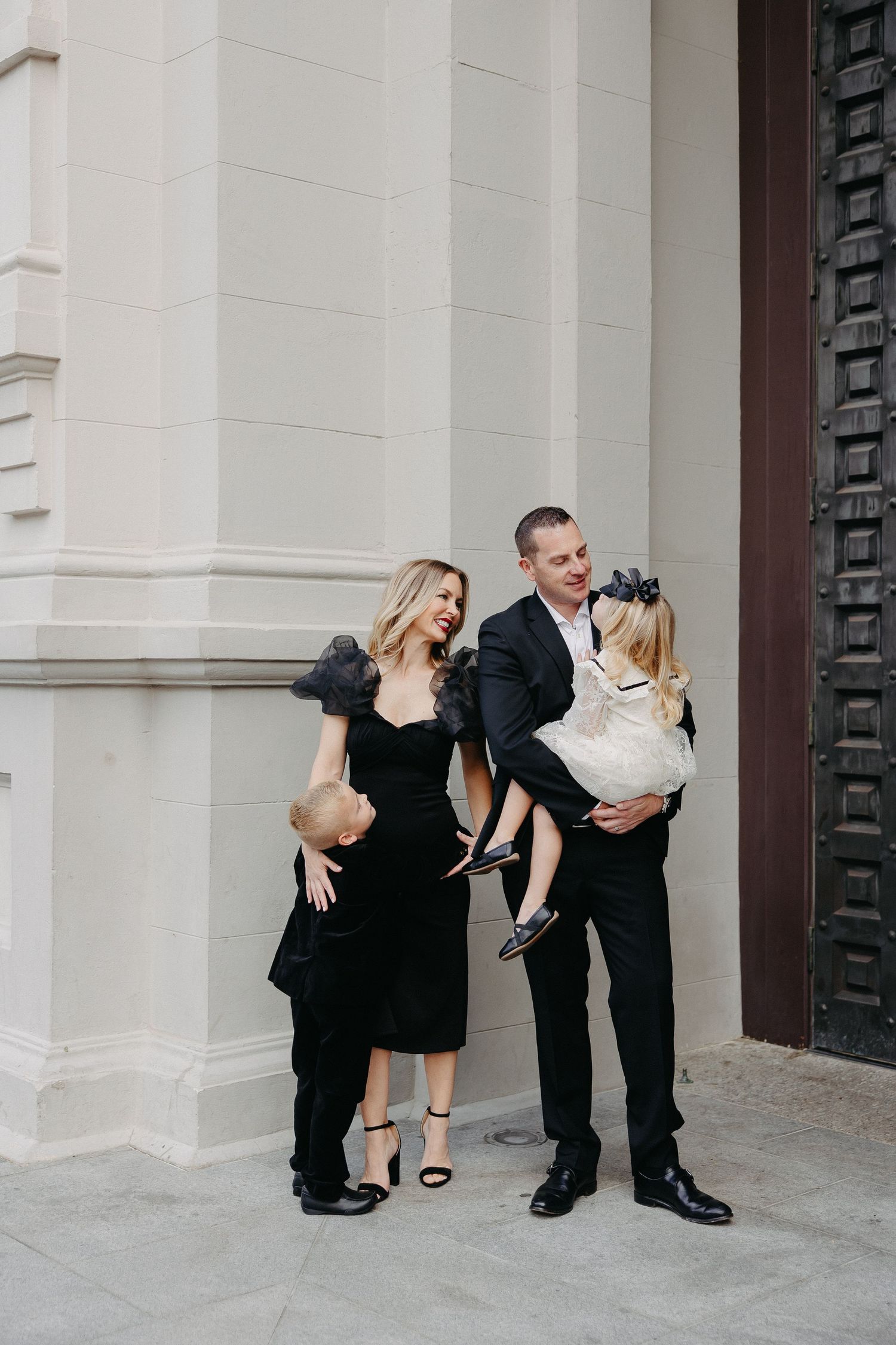 A formal family photo session outside a classical building with decorative doors.