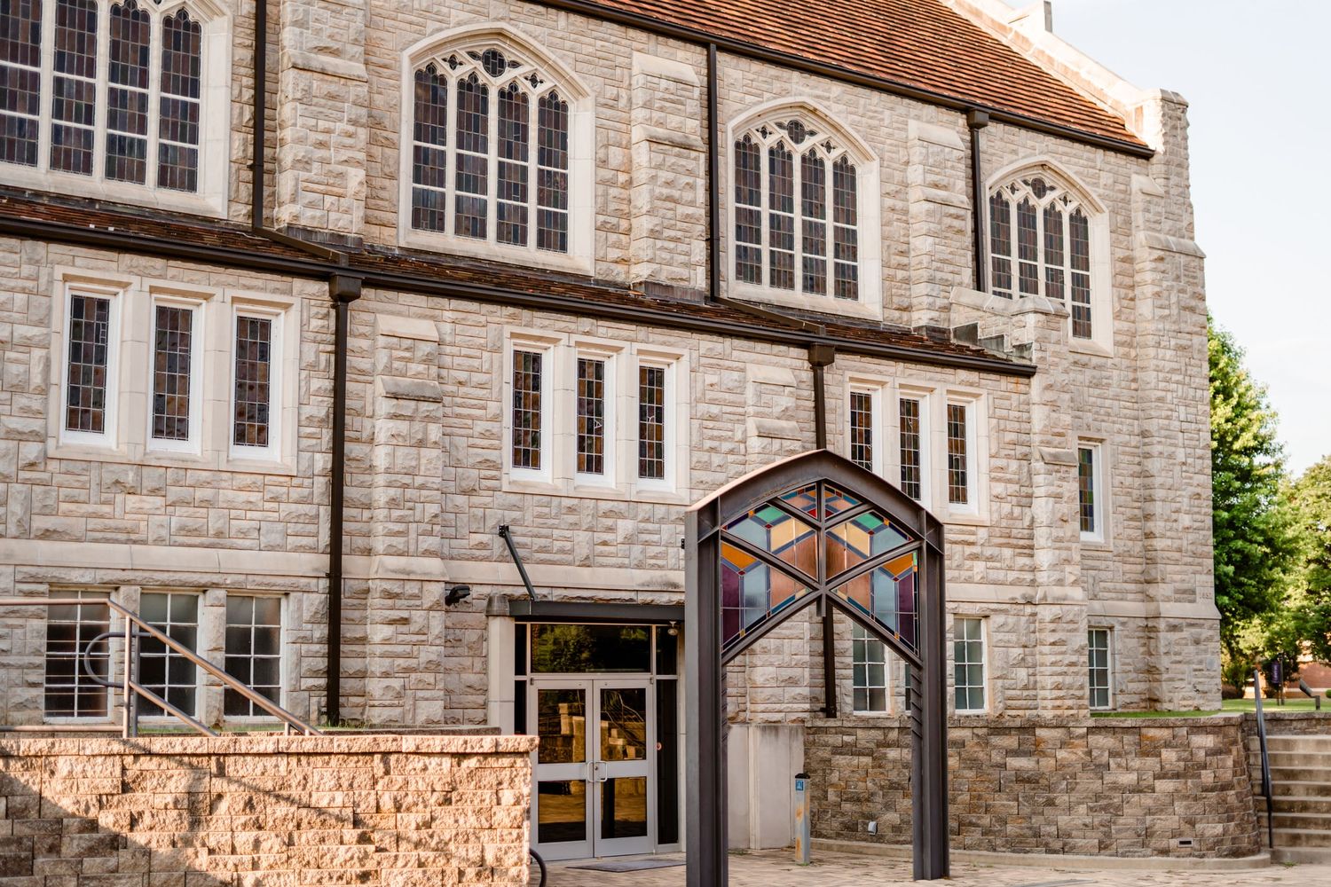 Gothic stone church exterior with arched windows and modern glass entrance.