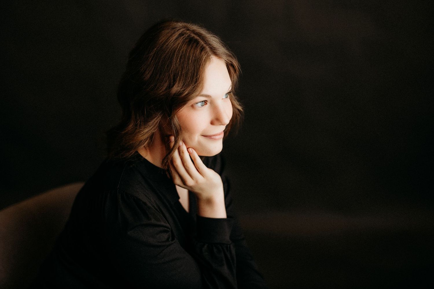 Artistic profile portrait with dark background showing contemplative expression.