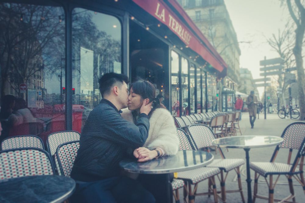 Couple kissing on a terrace of a romantic French cafe in Paris, France