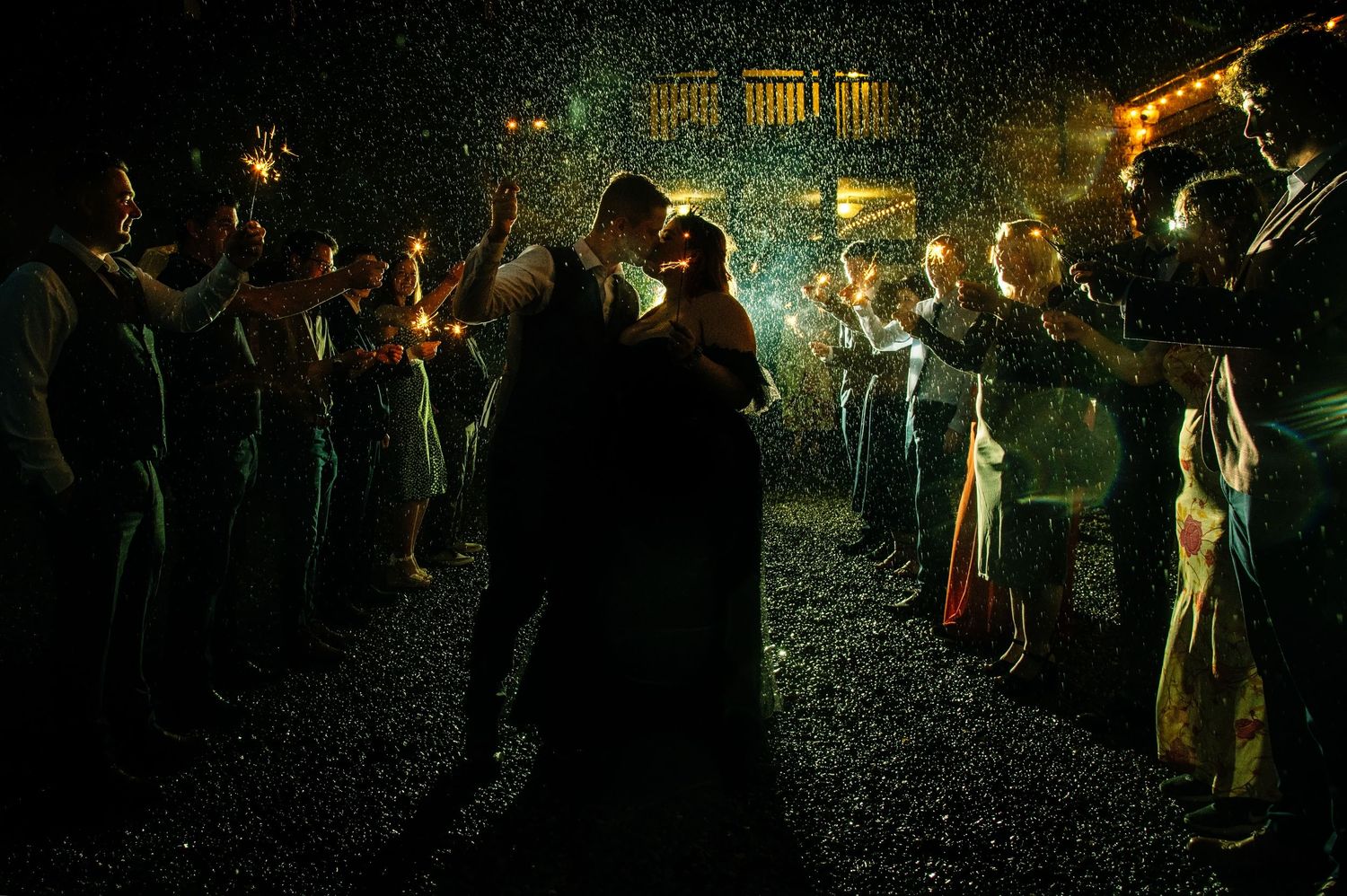 Dancing silhouettes enjoying a nighttime celebration with glowing lights in the background.