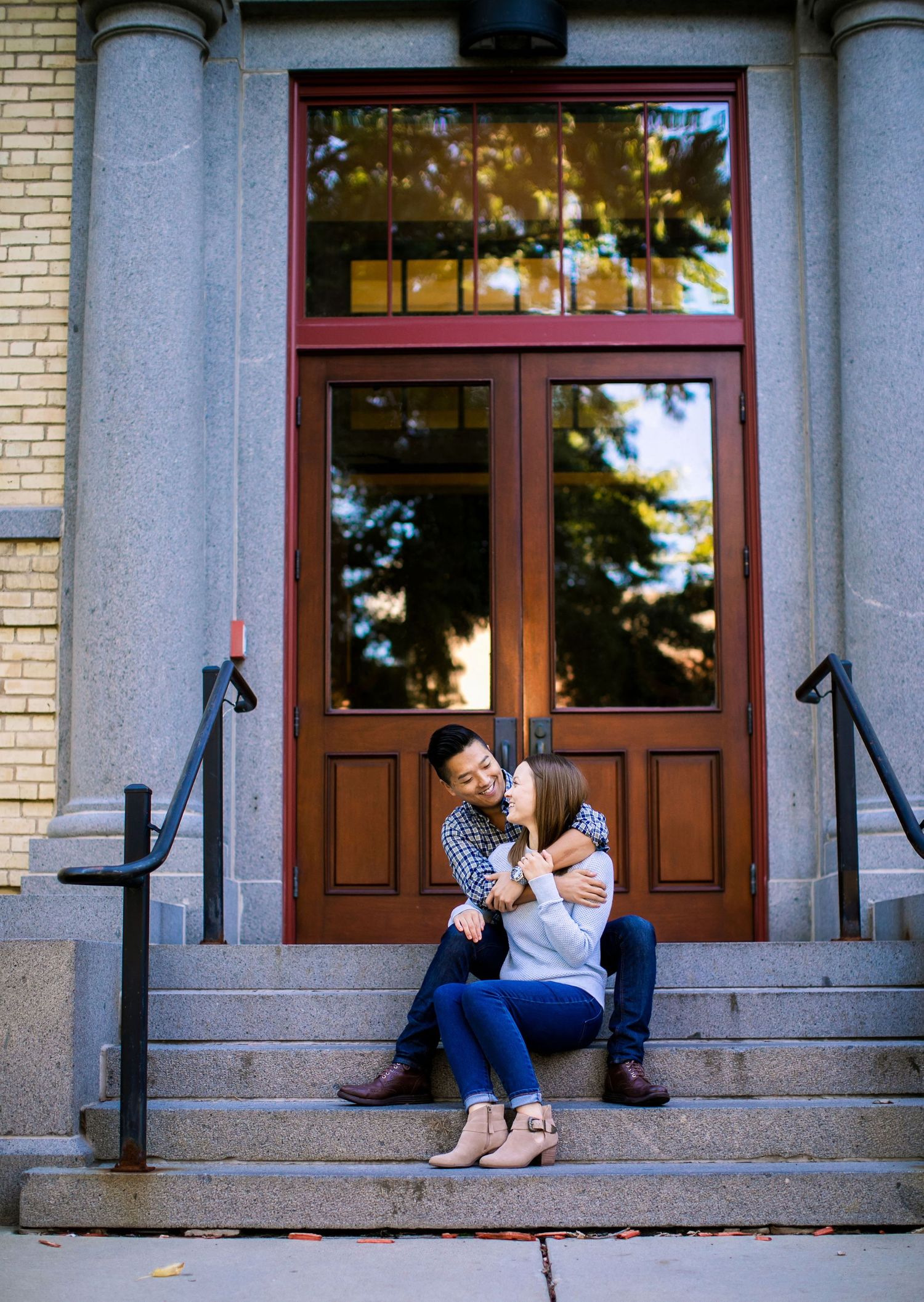 Couple cuddling on St. Cloud State University stairs during central Minnesota engagement photography session