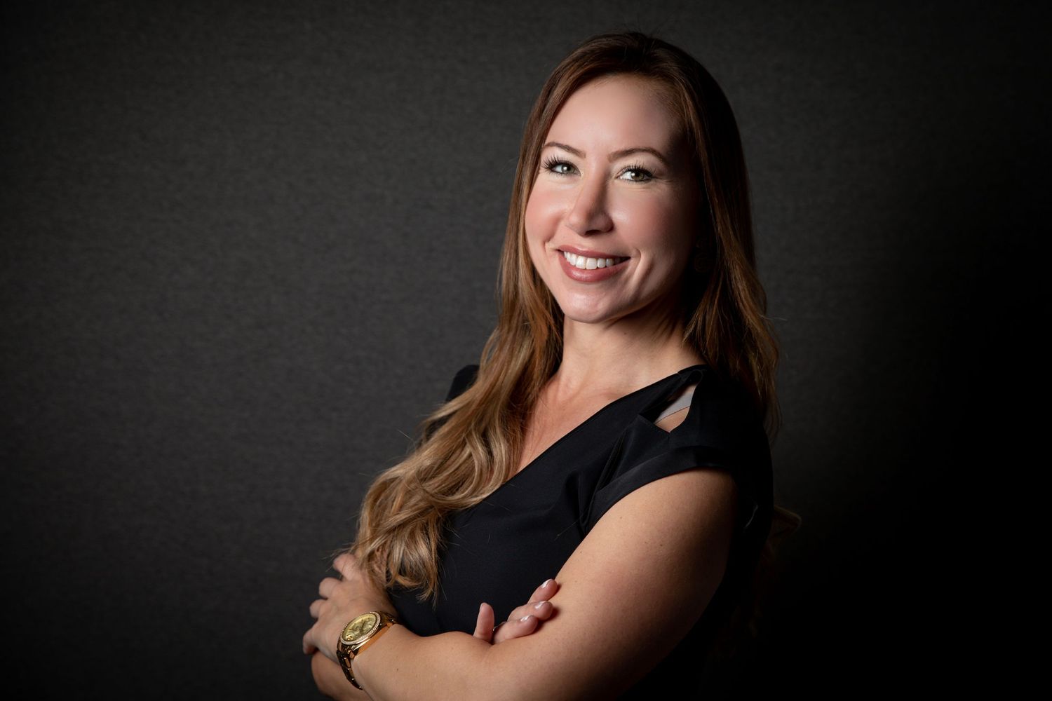 Professional studio portrait of someone in a black sleeveless top against a dark background.