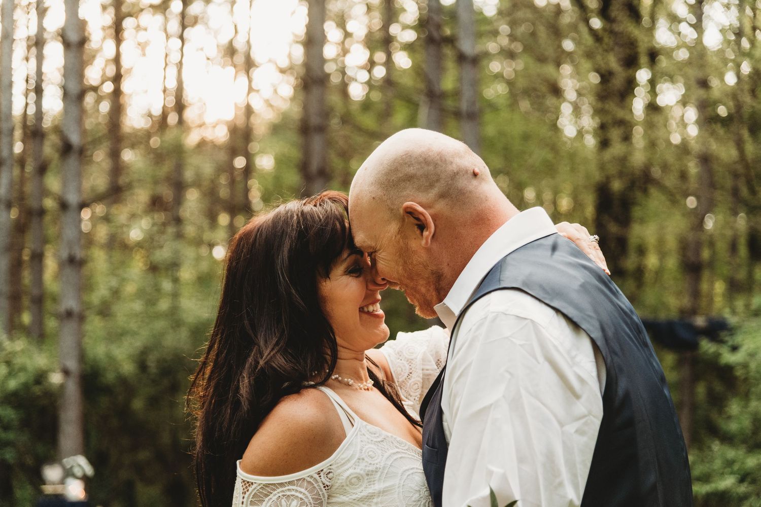Romantic couple sharing an intimate moment in a sunlit forest setting.