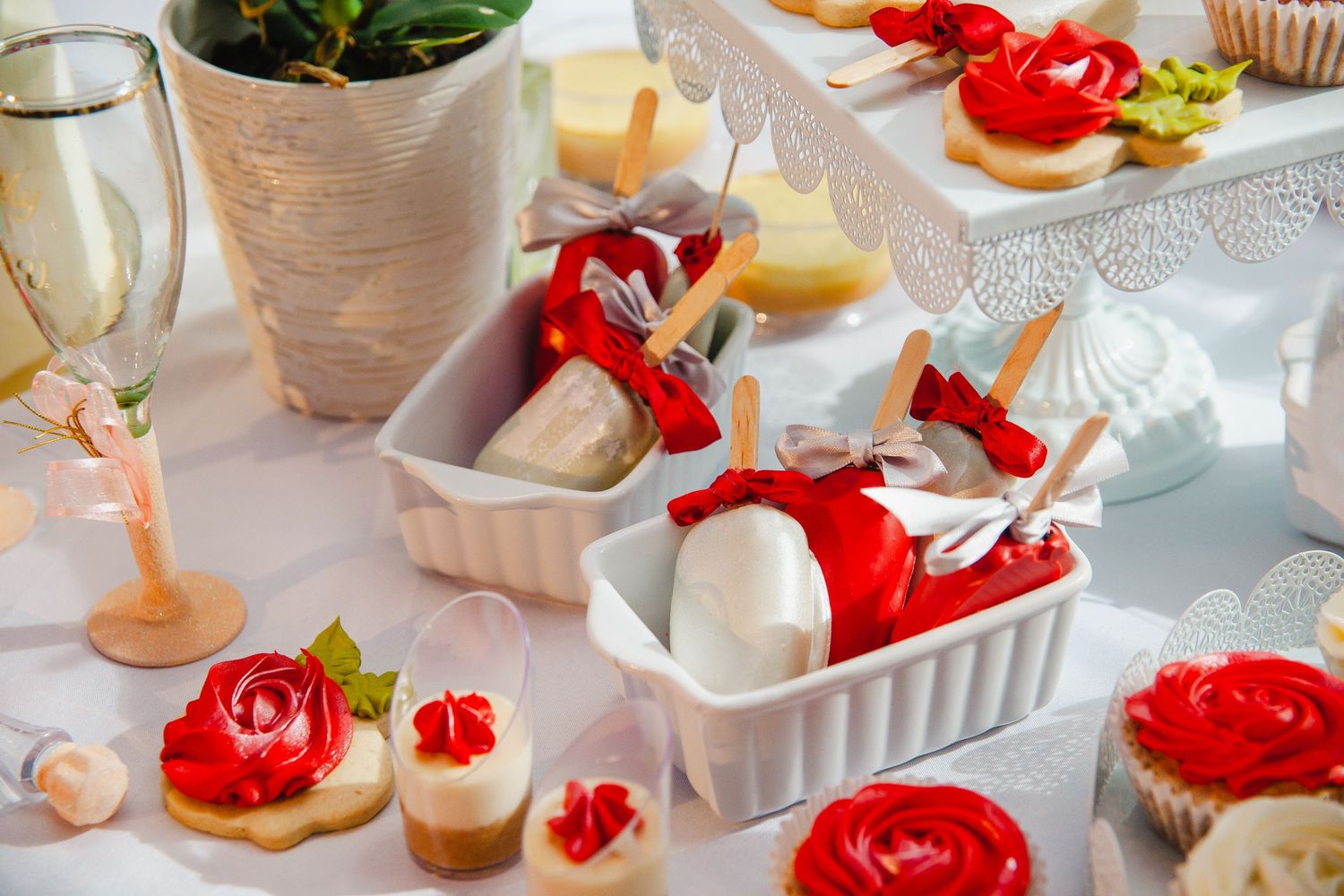 Elegant dessert table with white and red decorated cupcakes and sweet treats.