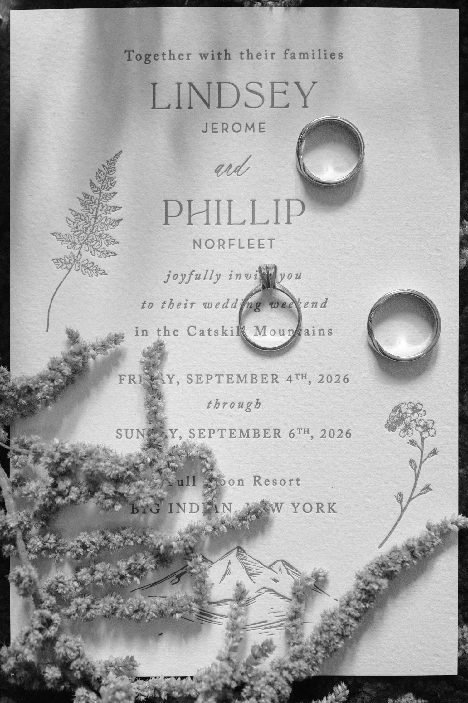Black and white photo of a bride sitting with bridesmaids in a rustic wooden room before the wedding ceremony.