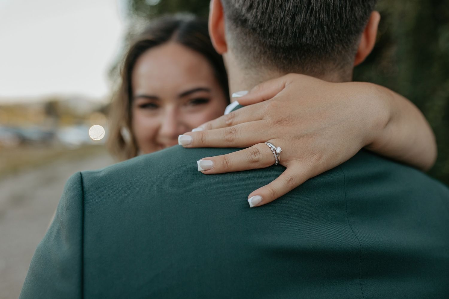 Close-up of engagement ring as couple embraces outdoors at Canopy Grove by Wedgewood Weddings.