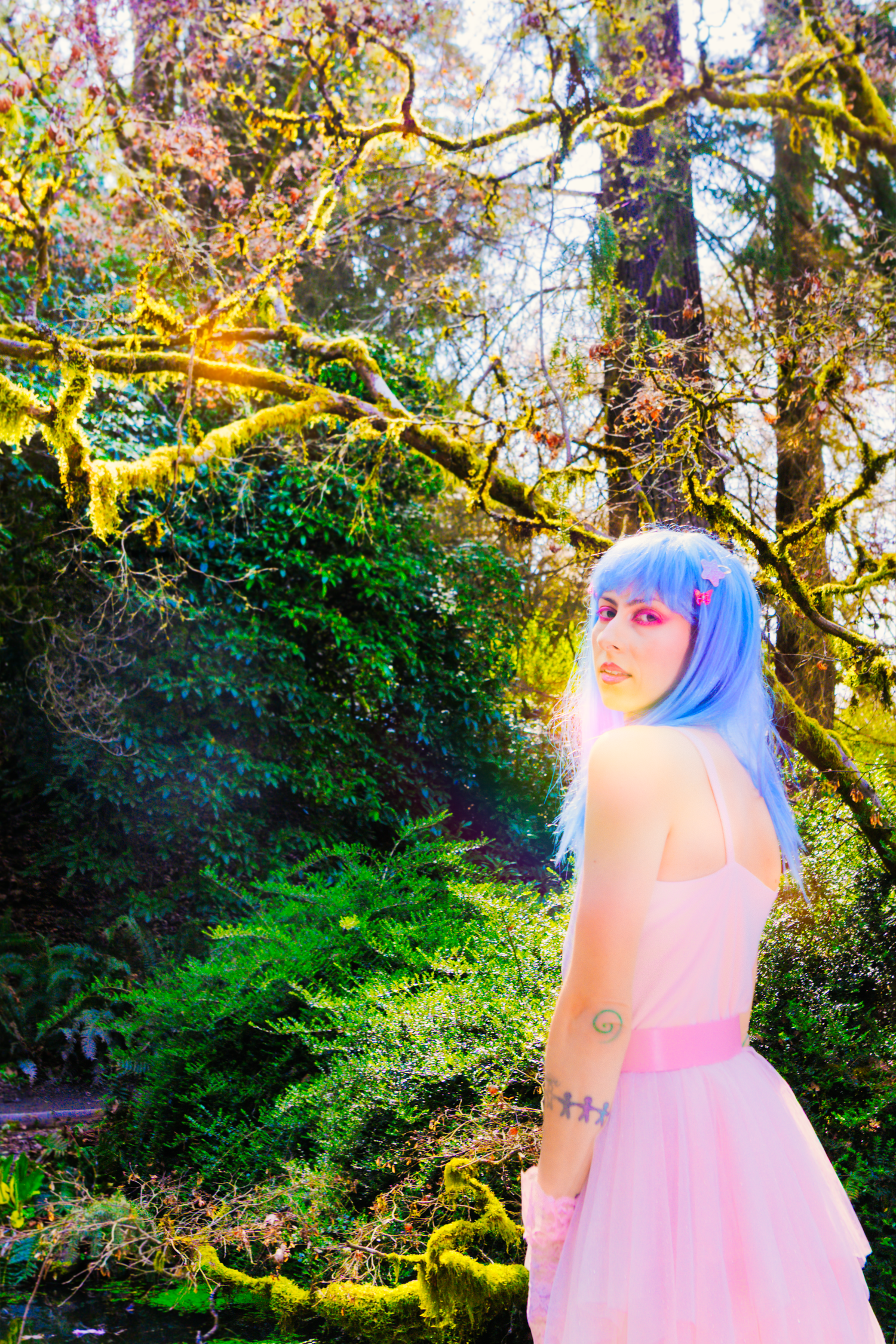 Ethereal portrait with bright blue hair and pink cherry blossoms creating a dreamy spring atmosphere.