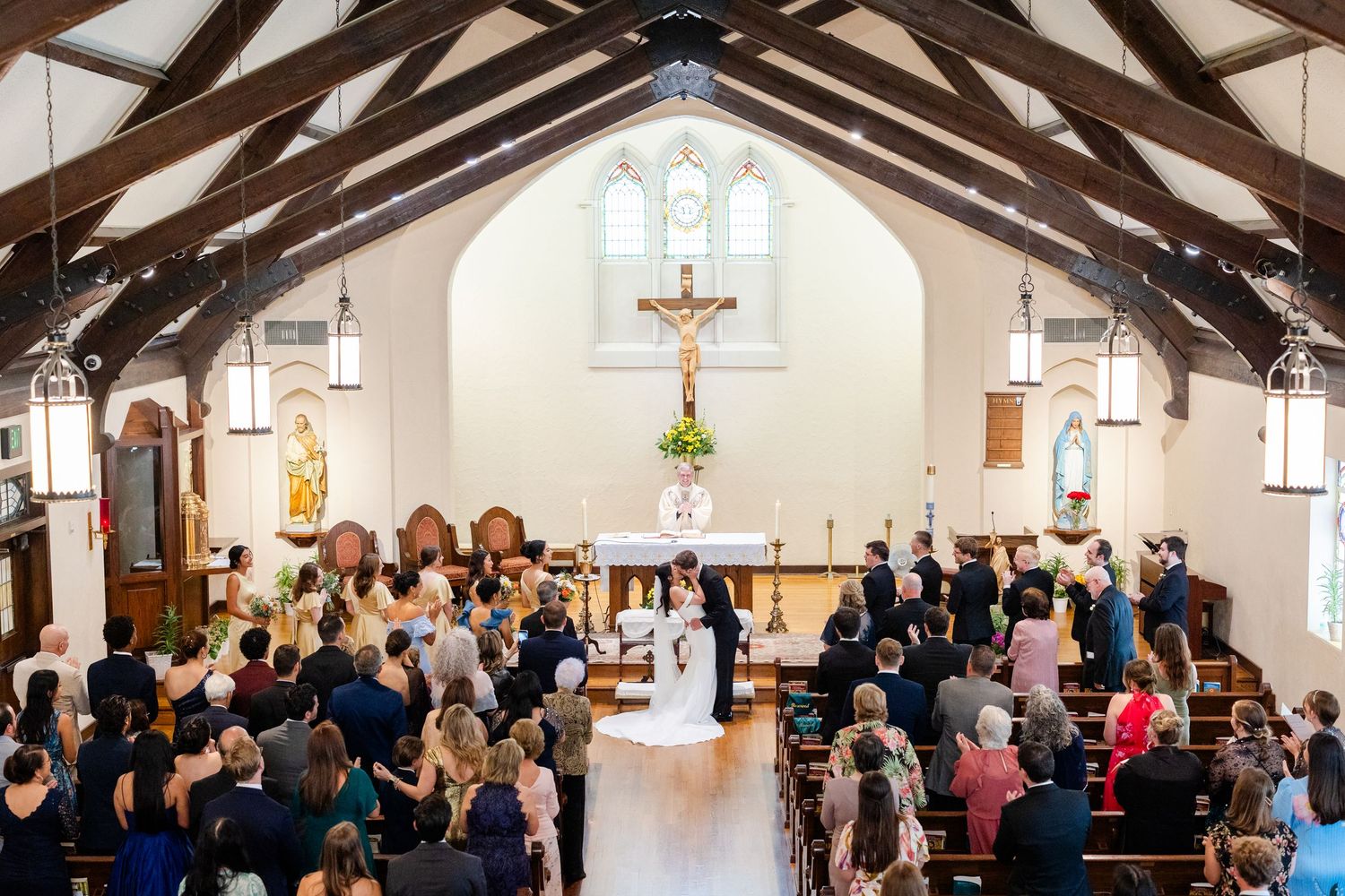 A large congregation gathers inside a church sanctuary during a religious service with arched ceilings and wooden beams.