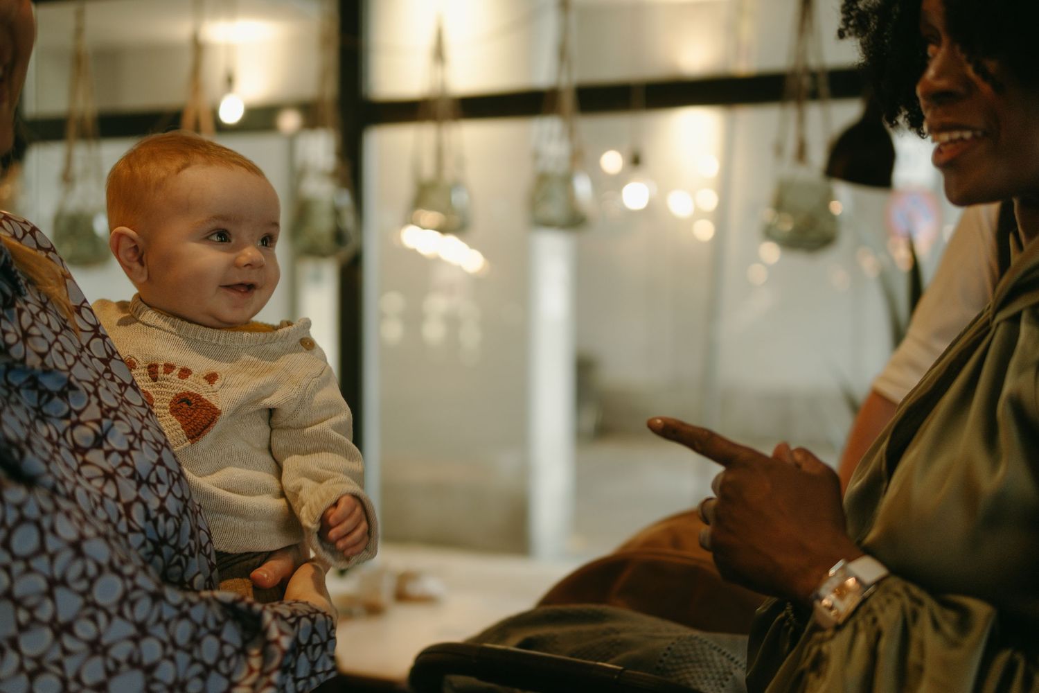 a baby held in her mother's arms smiling while being captured by event photographer in Stockholm