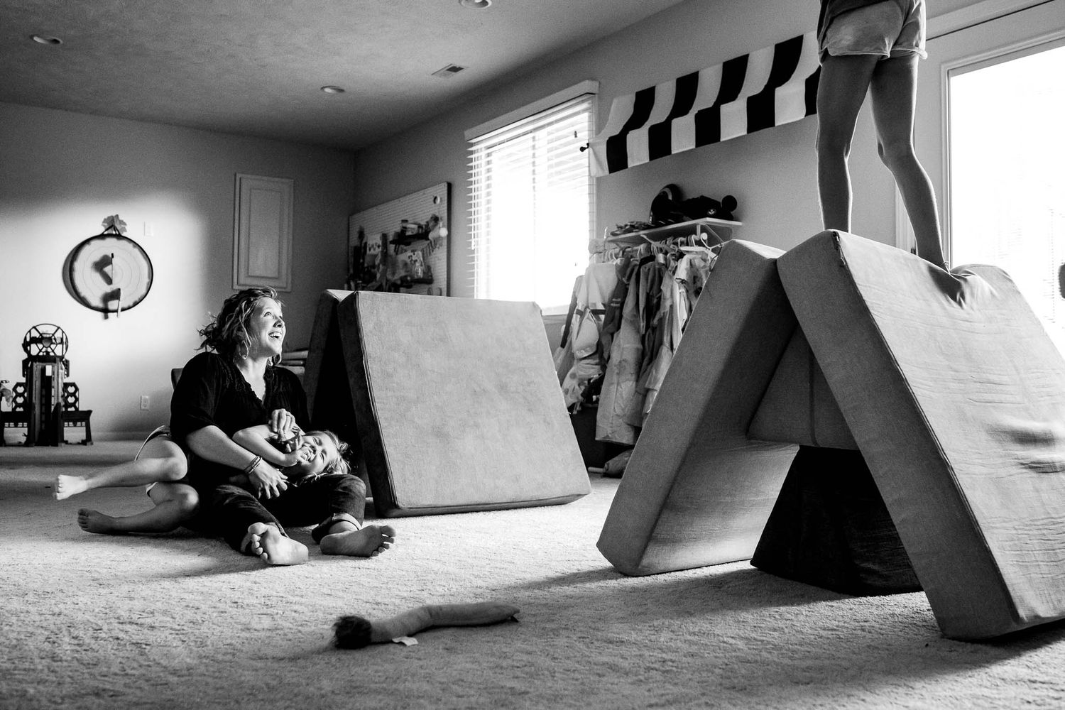 A black and white indoor scene showing a skate ramp setup in a carpeted room with racing flags on the wall.