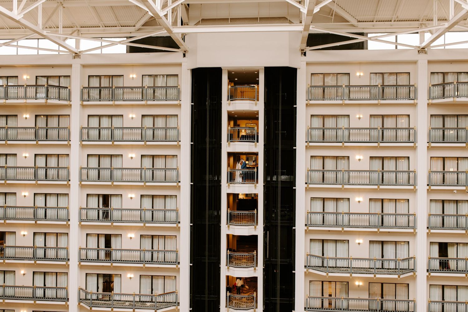 Architectural detail of a modern high-rise apartment building with beige balconies and a central black column design.