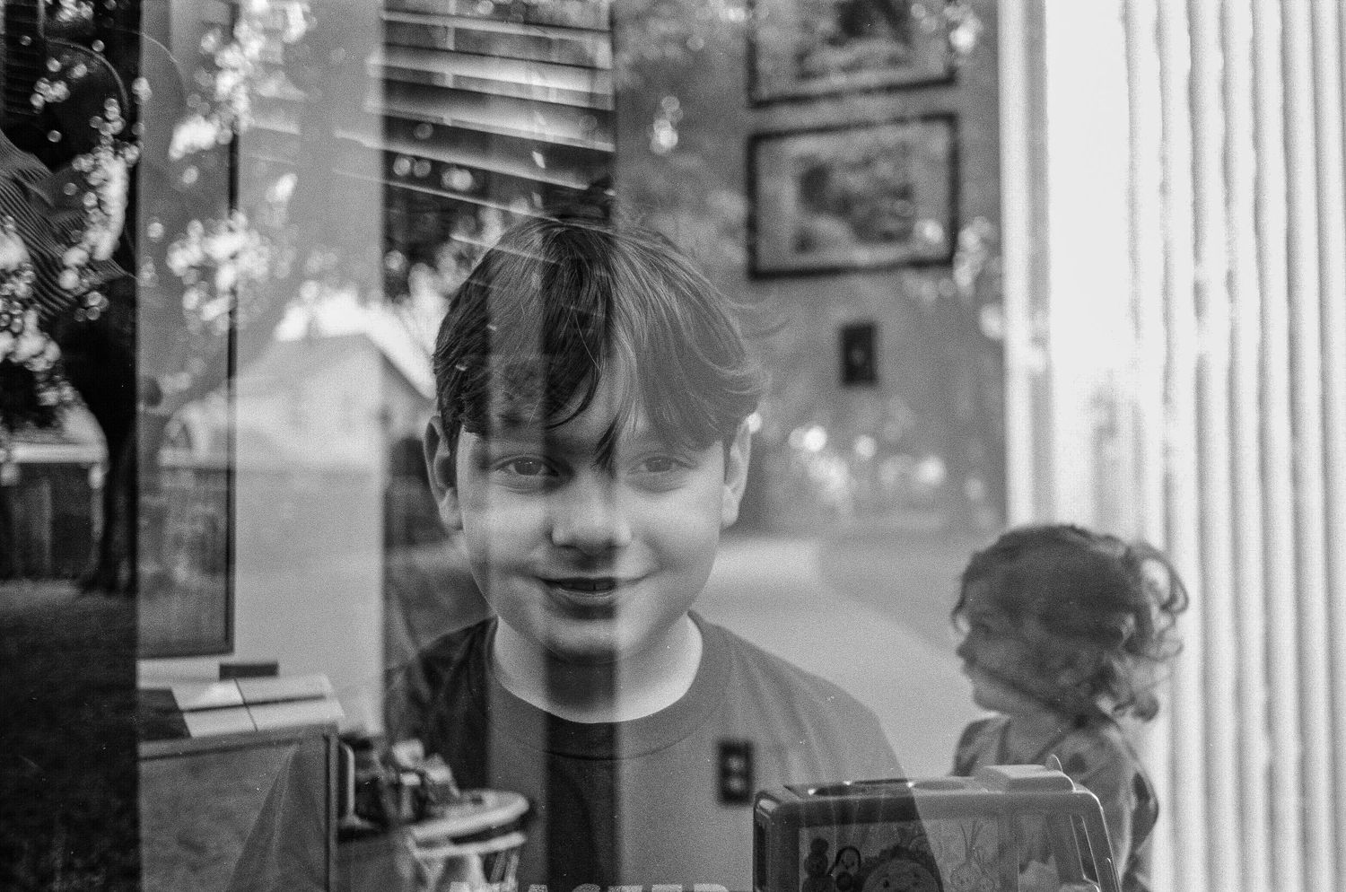 A black and white reflection of a face through glass with artistic double exposure effect.