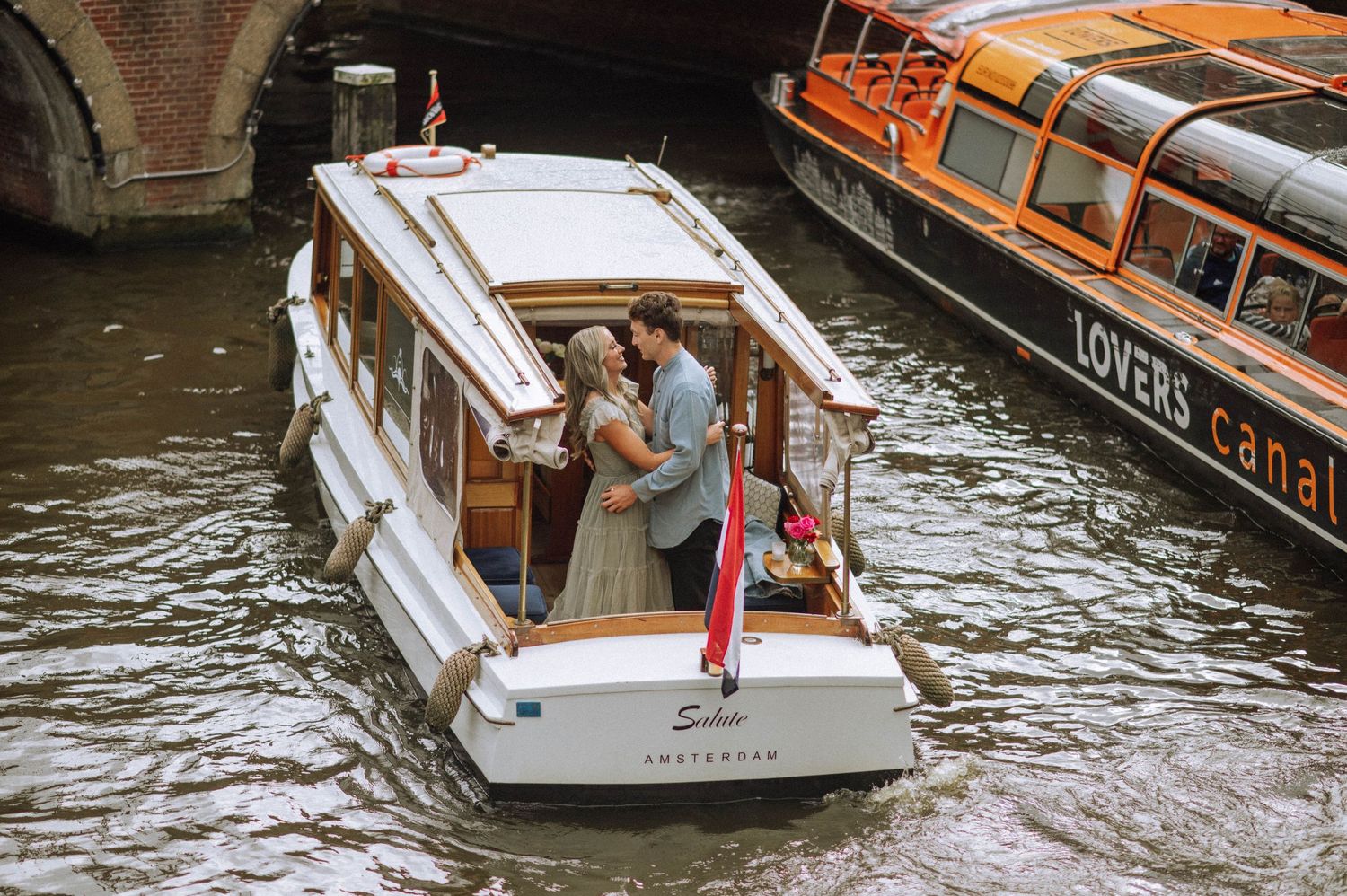 Couple smiling by Amsterdam canal during a love story photoshoot