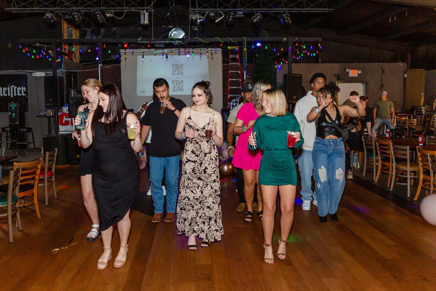 People dancing on a wooden floor at a casual indoor party venue.