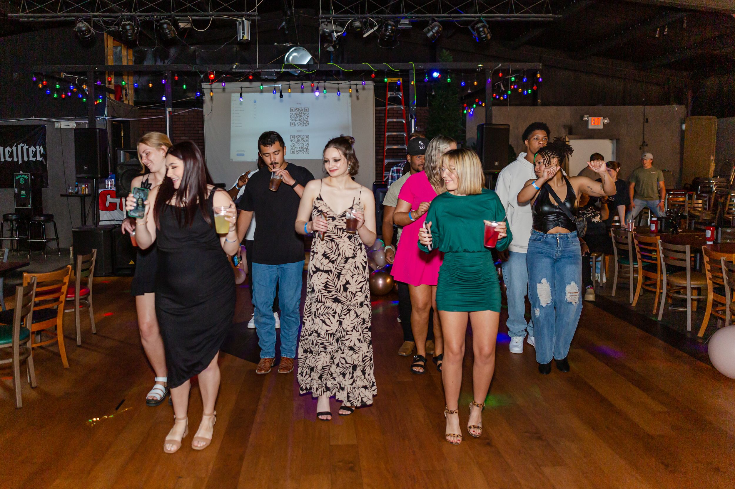 People dancing on a wooden floor at a casual indoor party venue.