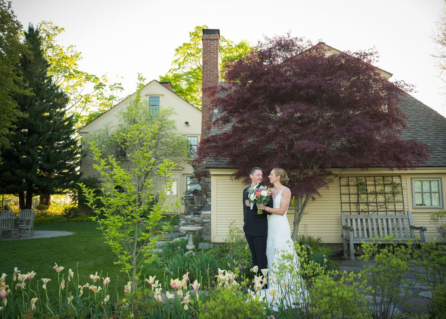 Romantic wedding couple poses in a spring garden with hanging white decorative spheres.