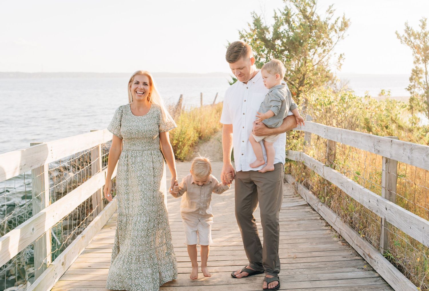 Family walking along bridge at Sandy Hook Beach during golden hour family photography session in New Jersey.
