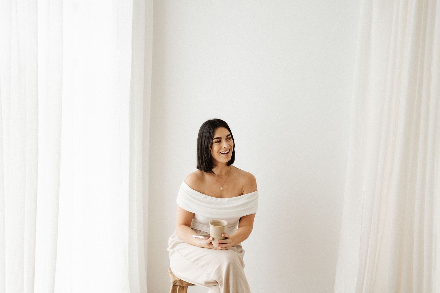 Elegant off-shoulder white dress photographed in bright natural light.
