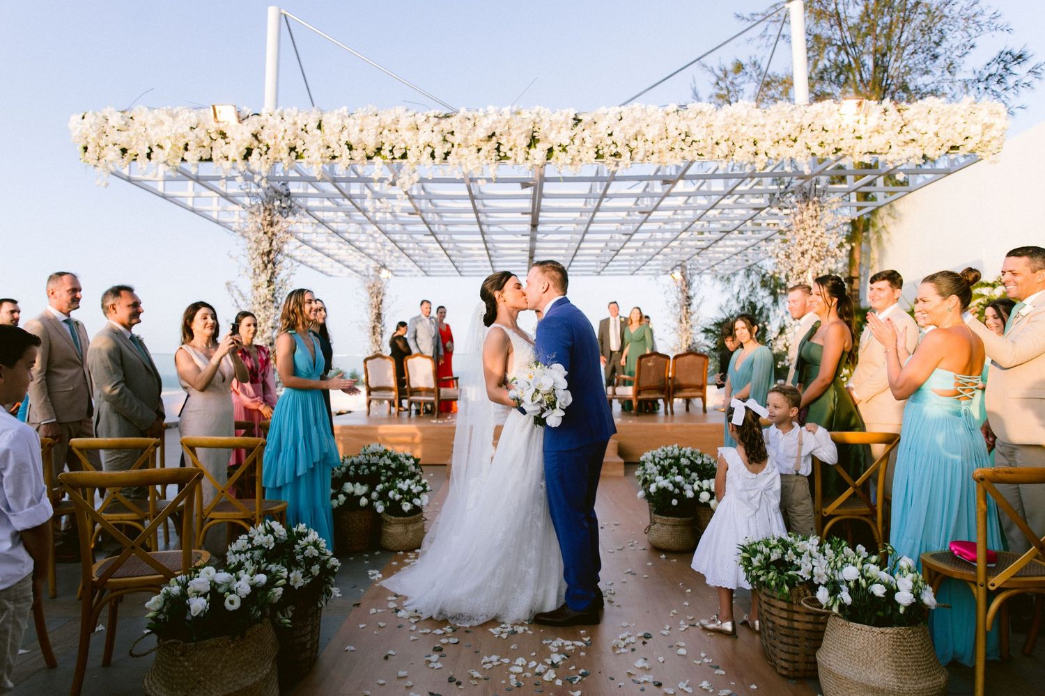 Wedding ceremony under a floral arch with guests watching.