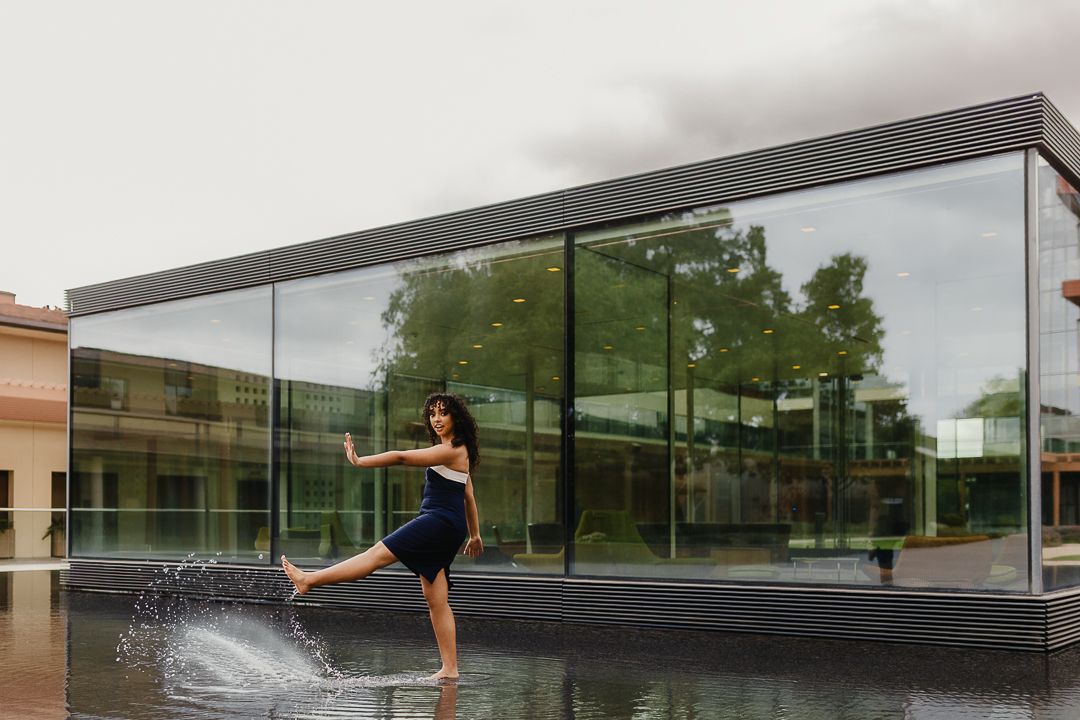 Girl in navy and white dress splashing in front of a glass structure