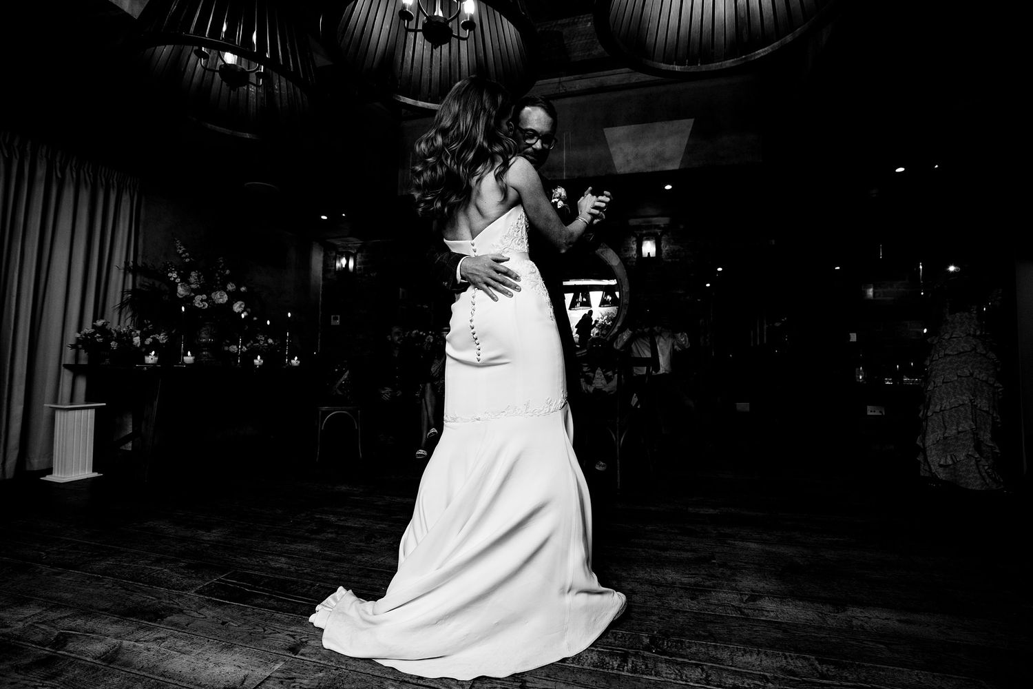 A couple shares their first dance at a wedding reception in the Halifax Tower Hotel in a dimly lit ballroom.