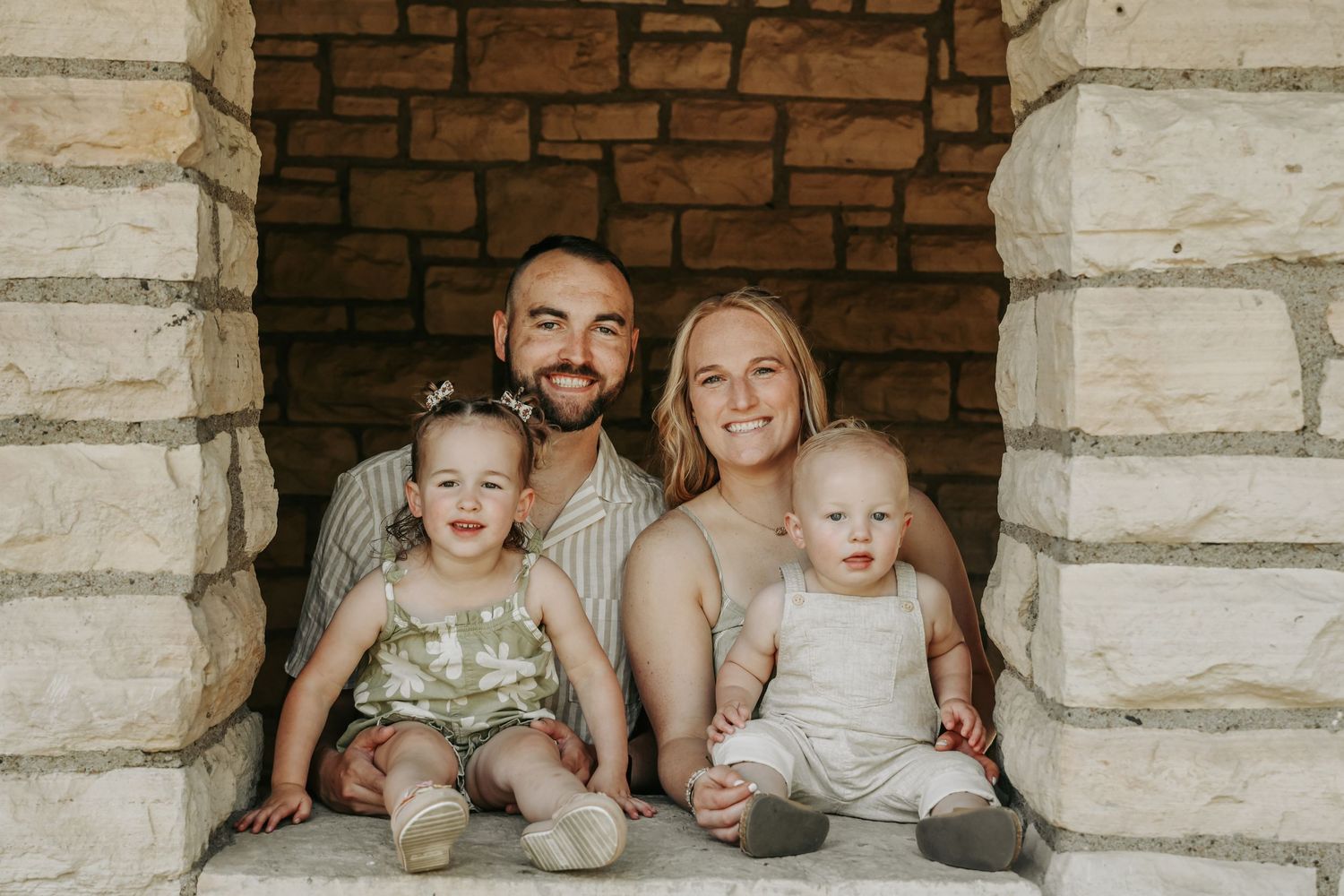 Family portrait in stone archway during outdoor photo session.