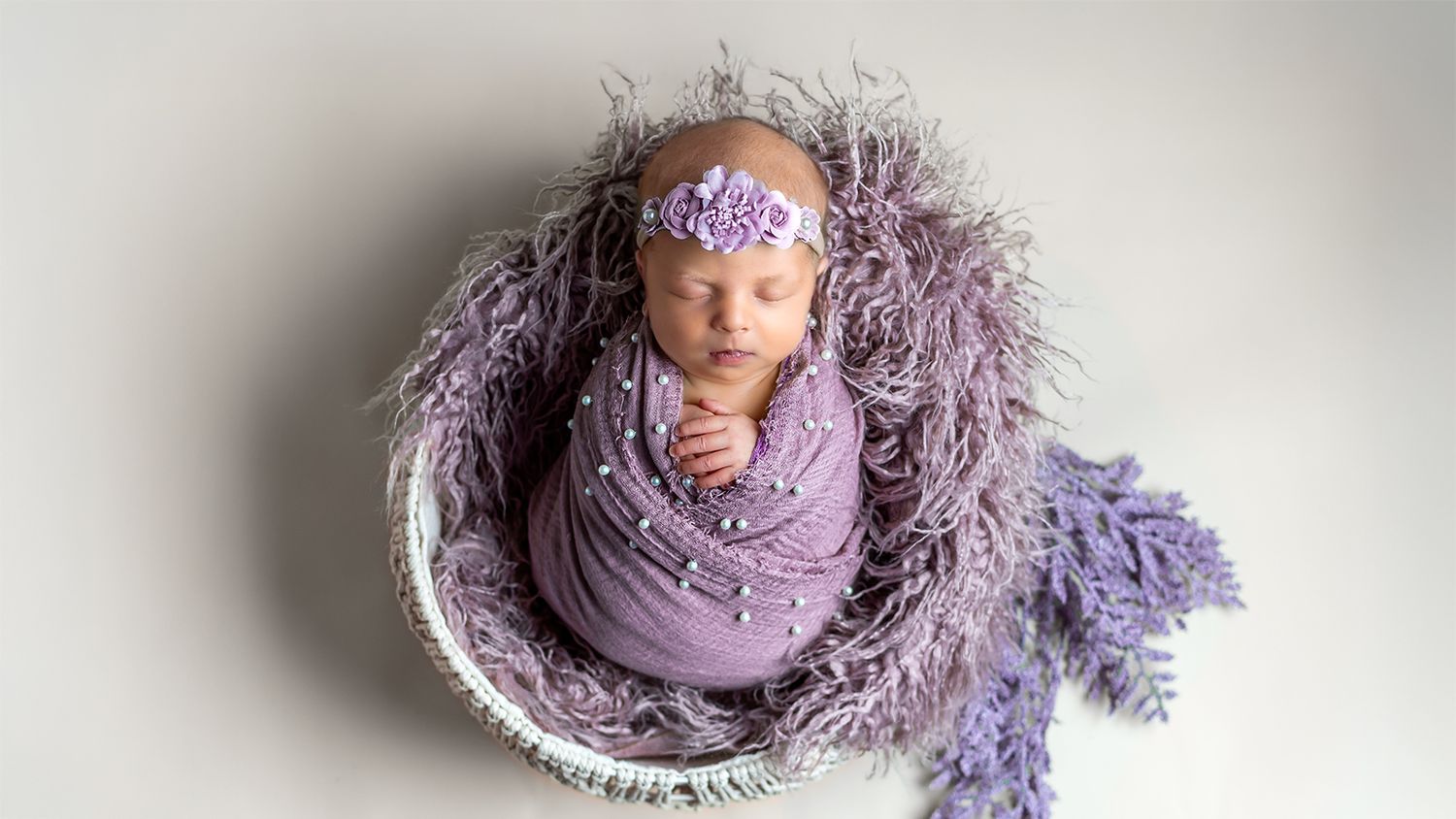 A series of newborn photography shots showing a sleeping baby wrapped in purple blankets and delicate lace textures.