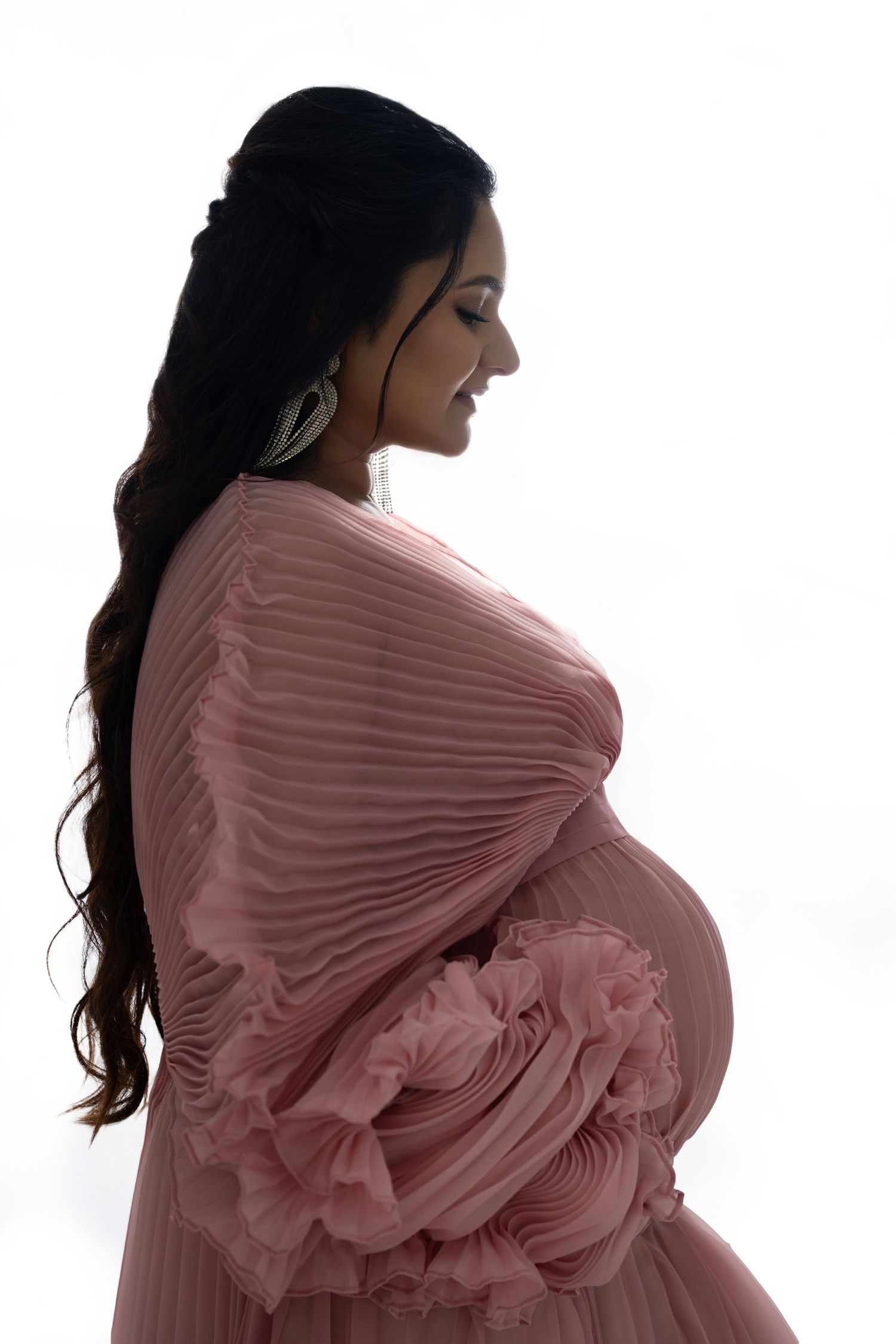 Luxury maternity photoshoot Dubai with flowing gown and dramatic lighting