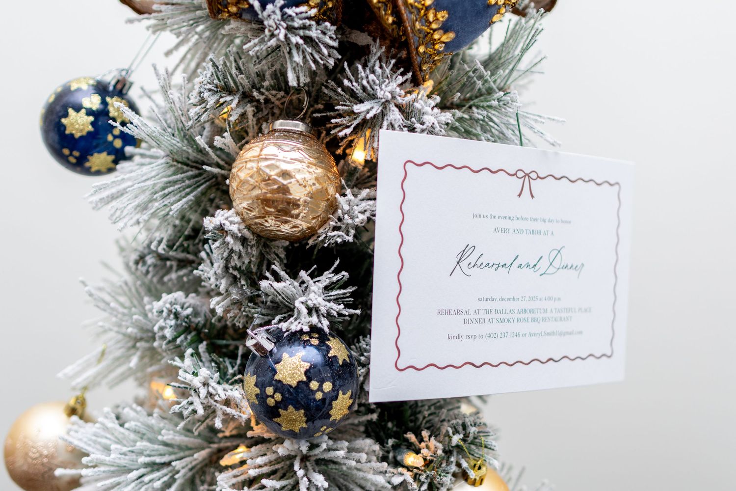 Close-up view of a decorated Christmas tree with frosted branches, blue and gold ornaments, and white paper cards.