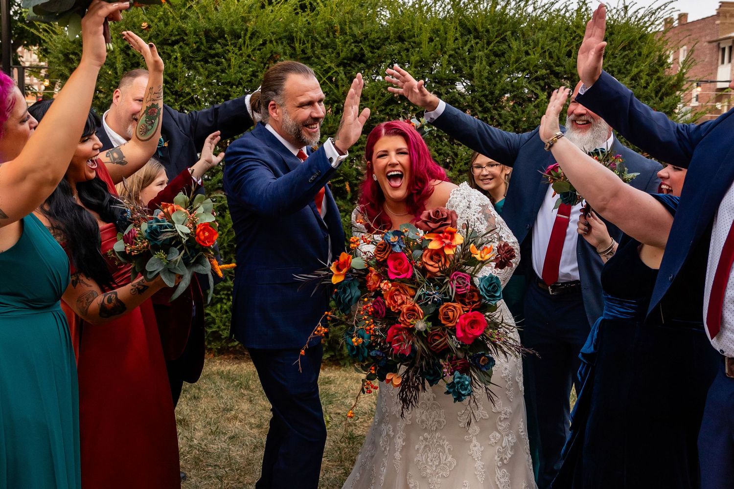 Joyful bride with red hair and groom celebrate with wedding party in navy and teal at Founders One Nine in Omaha, NE.
