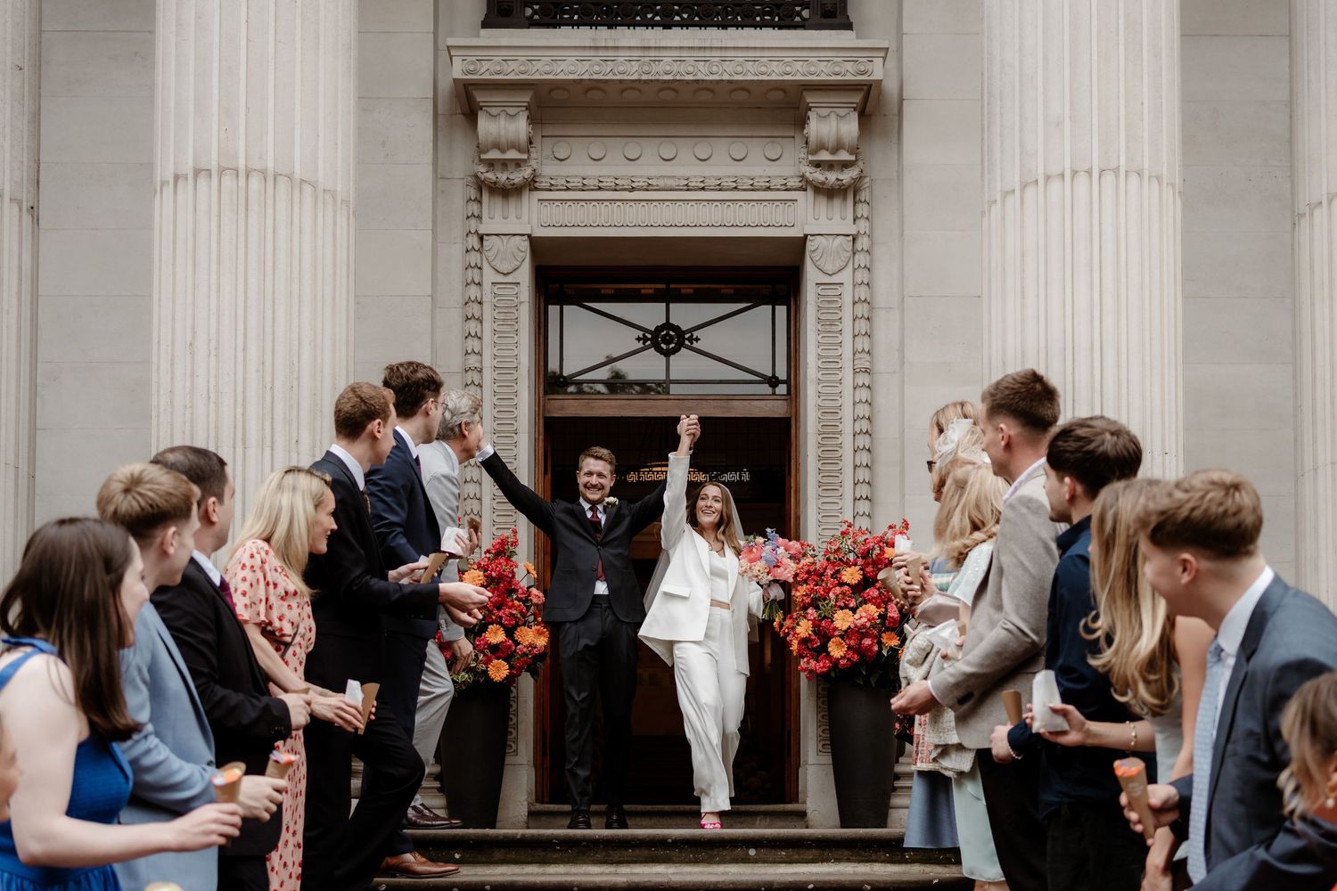 A panoramic collage of wedding guests gathered outside an elegant white columned building entrance during a celebration.