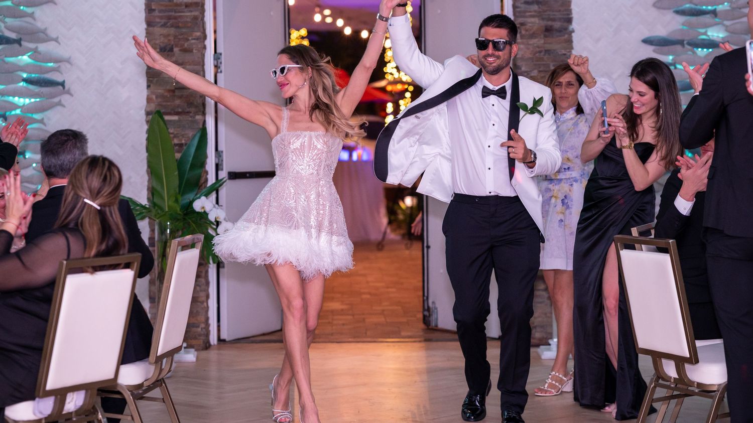 The bride and groom enter the reception to expecting guests waiting to celebrate with them. Captured by Treasure Coast wedding photographers