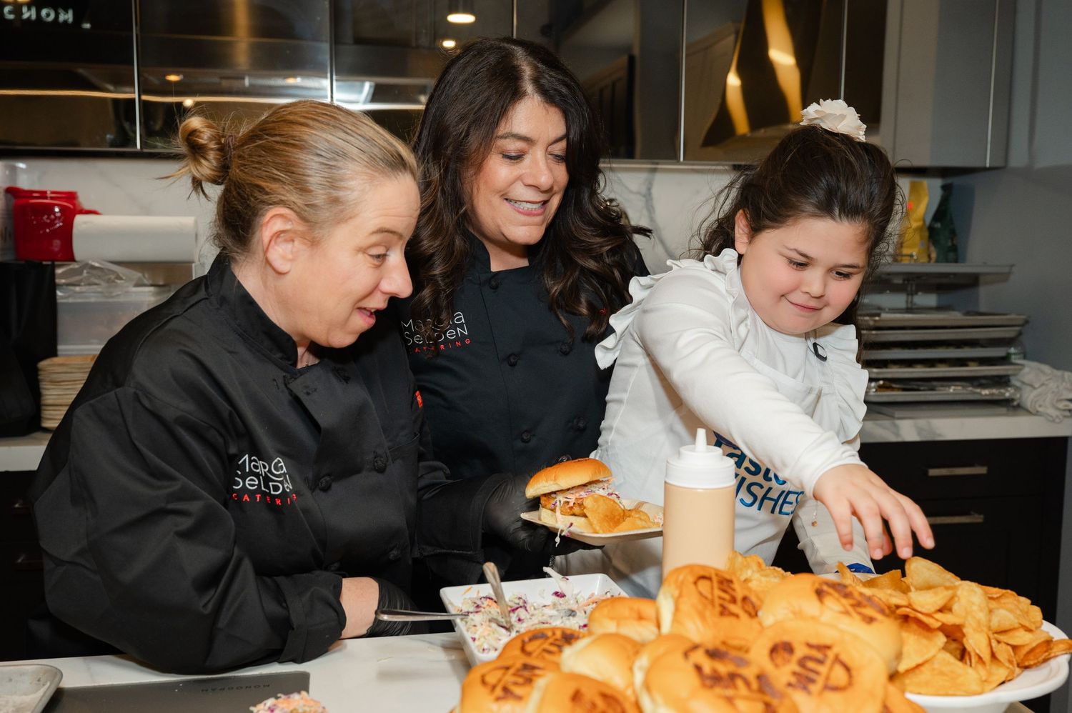 Three women and a girl enjoying baking together in a modern kitchen with fresh pastries.