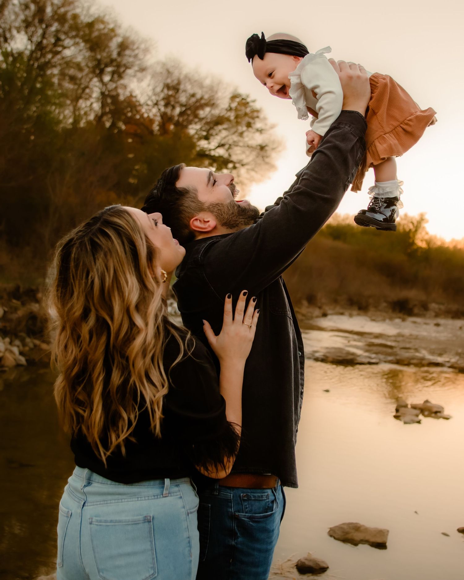 Family enjoying sunset moments together by a lake during a photo session.